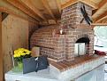 The half-barrel facade is complete. Hard to believe it contains a short, beavertail "Pompeii dome" oven. Note the firing door at the oven and the cooking door in front of the flowers.